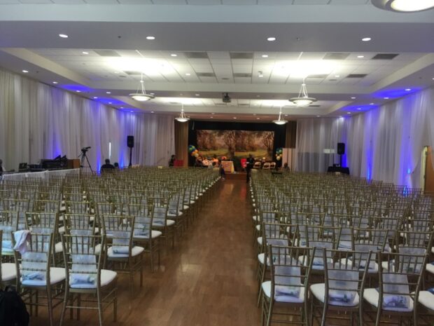 Ballroom concert setup with front lighting, speakers, and stage draping for church even