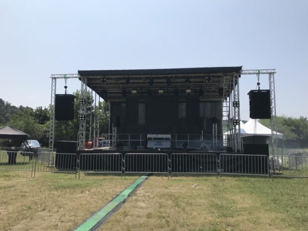 Outdoor concert stage setup with truss rigging, full lighting rig, and speaker arrays