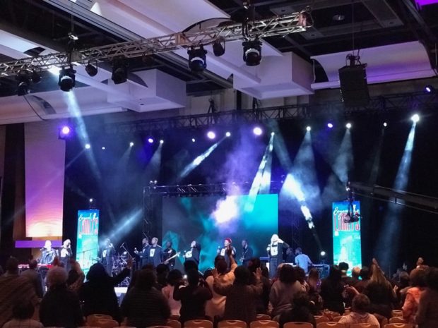 featuring stage lighting, LED video walls, and audience engagement at an indoor event.